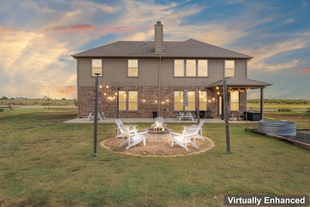 back house at dusk with a patio, a lawn, and an outdoor fire pit