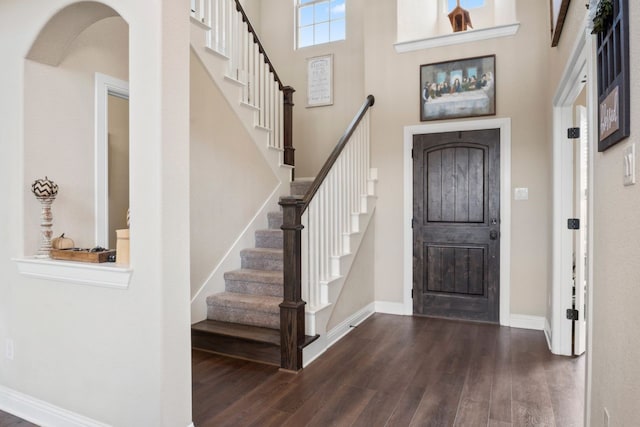 foyer entrance with dark hardwood / wood-style flooring and a towering ceiling