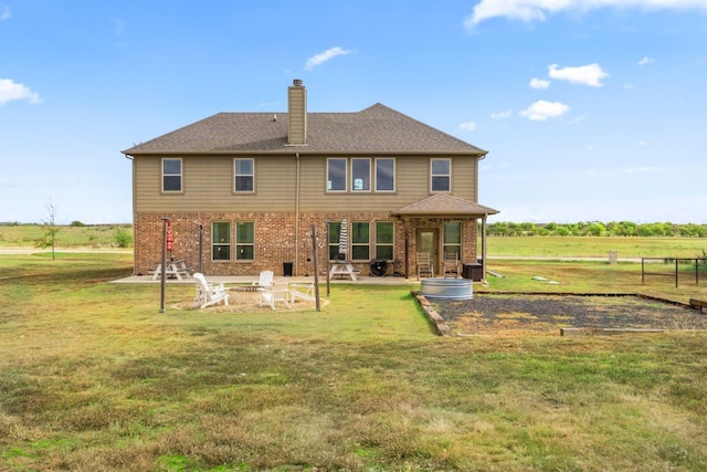 back of property featuring a patio area, a rural view, a lawn, and an outdoor fire pit