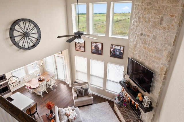 living room with a high ceiling, ceiling fan with notable chandelier, and dark hardwood / wood-style flooring