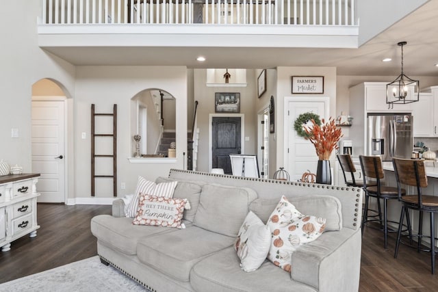 living room featuring a towering ceiling, dark hardwood / wood-style flooring, and a notable chandelier