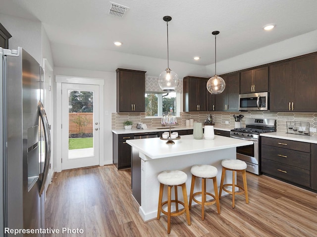 kitchen with dark brown cabinets, a kitchen island, and appliances with stainless steel finishes