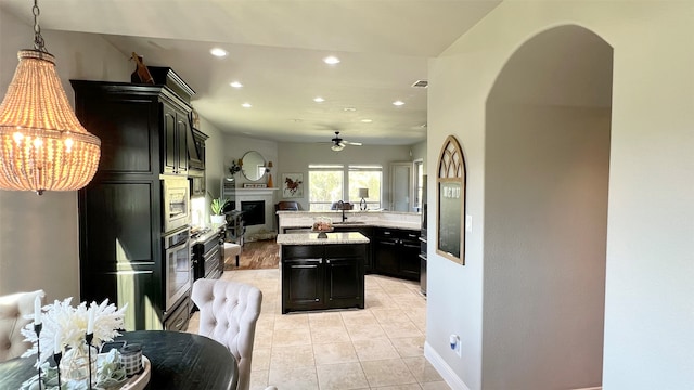 kitchen with ceiling fan, stainless steel appliances, light tile patterned floors, pendant lighting, and a kitchen island