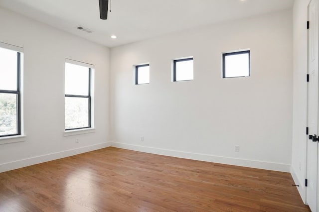 empty room featuring ceiling fan, wood-type flooring, and a healthy amount of sunlight