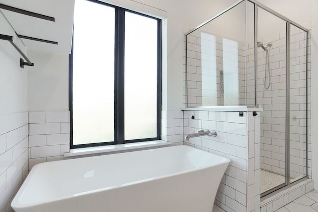 bathroom featuring tile walls, a wealth of natural light, tile patterned floors, and separate shower and tub