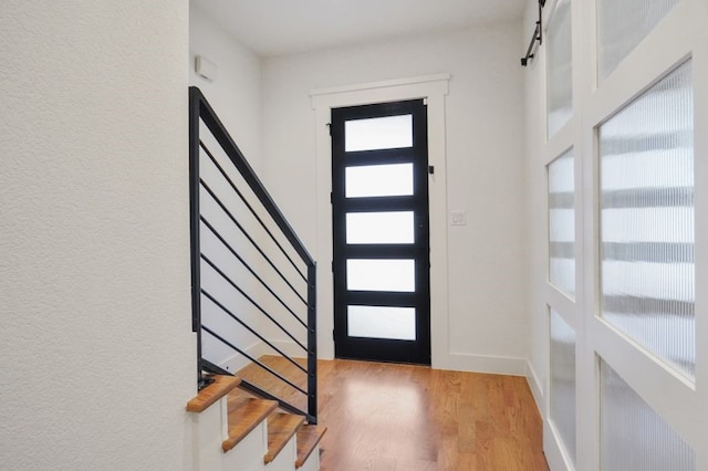 foyer entrance with light wood-type flooring, plenty of natural light, and a barn door