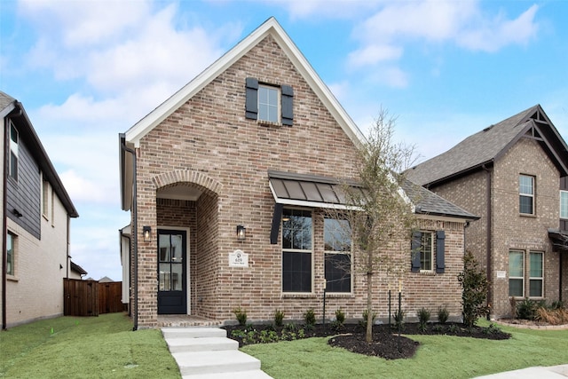 traditional home with a front yard, fence, and brick siding