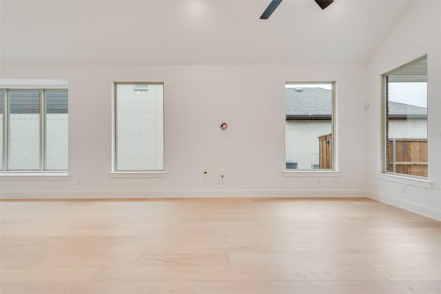 empty room featuring lofted ceiling, light wood-type flooring, a ceiling fan, and baseboards