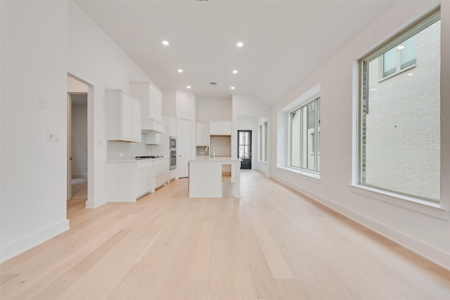 kitchen featuring light countertops, a sink, a kitchen island with sink, and white cabinets