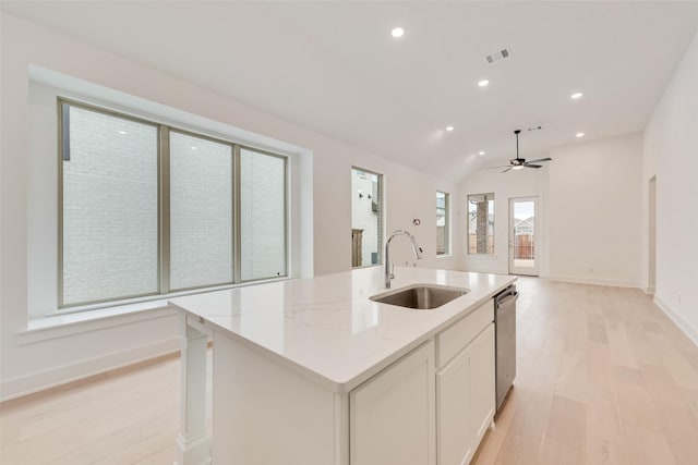 kitchen featuring a sink, white cabinetry, light stone countertops, dishwasher, and an island with sink