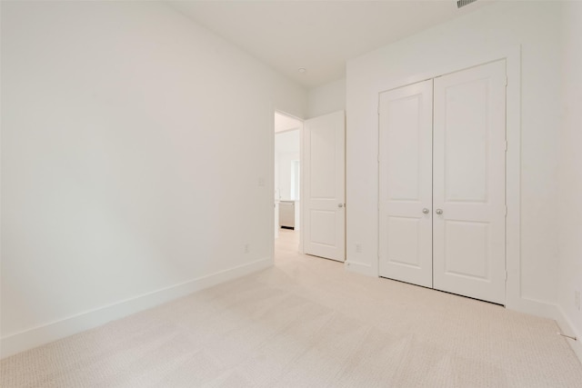 unfurnished bedroom with visible vents, baseboards, a closet, and light colored carpet