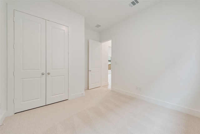 unfurnished bedroom featuring a closet, visible vents, light carpet, and baseboards