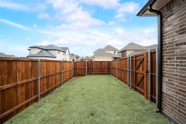 view of yard featuring a fenced backyard, a residential view, and a gate