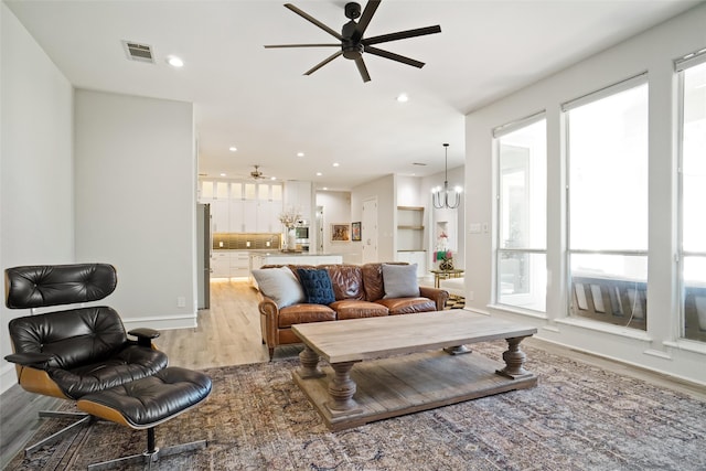 living room with light hardwood / wood-style flooring, sink, ceiling fan with notable chandelier, and plenty of natural light