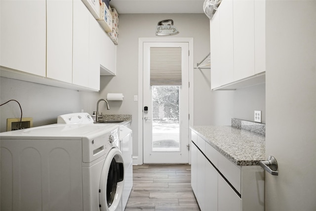 clothes washing area featuring sink, light wood-type flooring, cabinets, and washing machine and clothes dryer