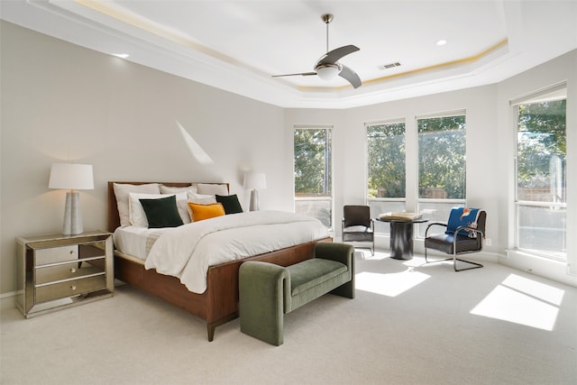 bedroom with ceiling fan, a tray ceiling, and light colored carpet