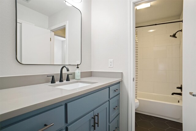 full bathroom featuring vanity, tile patterned flooring, toilet, and tiled shower / bath