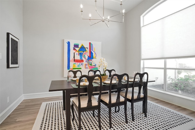 dining space featuring a towering ceiling, light wood-type flooring, and a chandelier