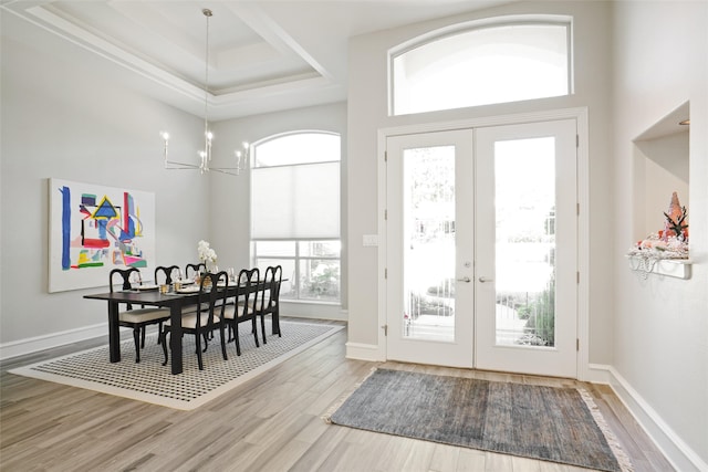 dining area featuring french doors, a raised ceiling, hardwood / wood-style flooring, and a chandelier