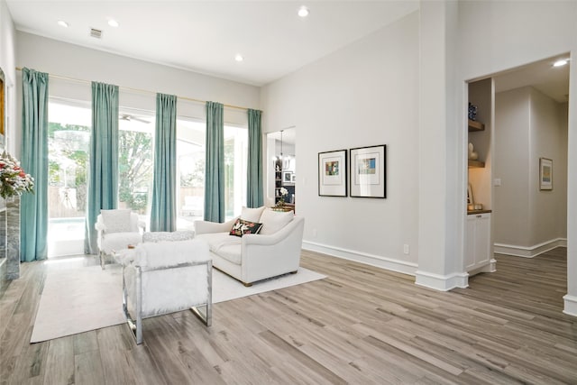 living room featuring a high ceiling, a notable chandelier, and light hardwood / wood-style floors