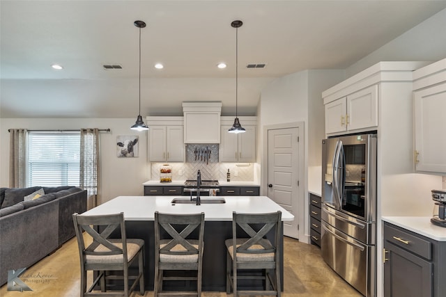 kitchen with a kitchen island with sink, stainless steel appliances, sink, tasteful backsplash, and pendant lighting