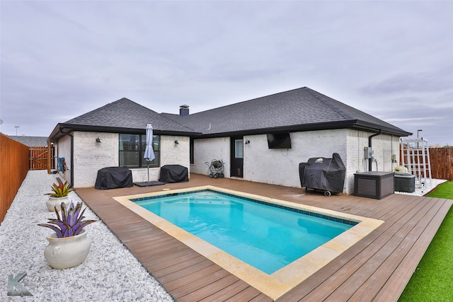 view of pool with grilling area and a deck