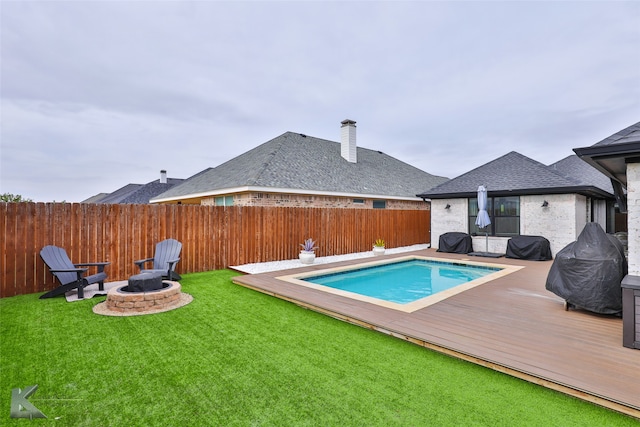 view of swimming pool featuring an outdoor fire pit, a lawn, and a wooden deck