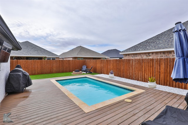 view of pool with a wooden deck and an outdoor fire pit