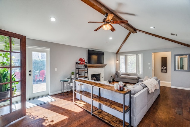 living room featuring a brick fireplace, plenty of natural light, hardwood / wood-style flooring, and vaulted ceiling with beams