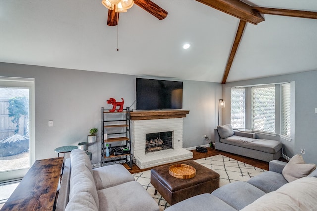 living room with a brick fireplace, lofted ceiling with beams, light hardwood / wood-style flooring, and ceiling fan