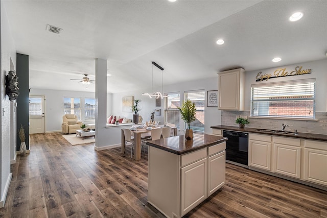 kitchen featuring sink, decorative light fixtures, dishwasher, a kitchen island, and backsplash