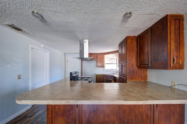 kitchen with kitchen peninsula, a textured ceiling, sink, wall chimney range hood, and stainless steel electric range oven