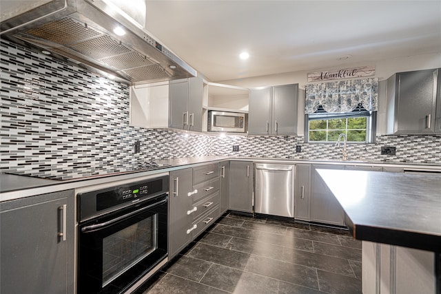 kitchen featuring black appliances, sink, gray cabinets, wall chimney range hood, and backsplash