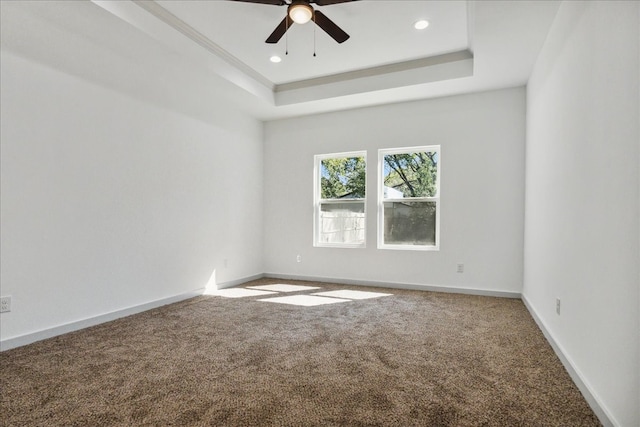 unfurnished room with carpet flooring, ceiling fan, and a raised ceiling