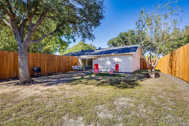 back of house with a lawn and a patio