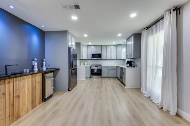 kitchen featuring gray cabinetry, sink, light hardwood / wood-style floors, and stainless steel appliances