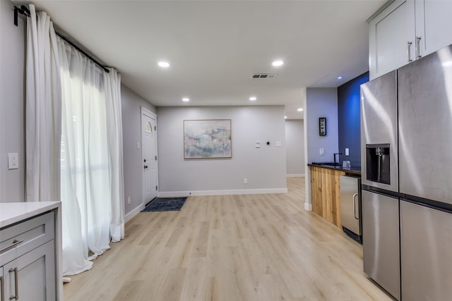 kitchen featuring stainless steel fridge, gray cabinetry, and light hardwood / wood-style flooring