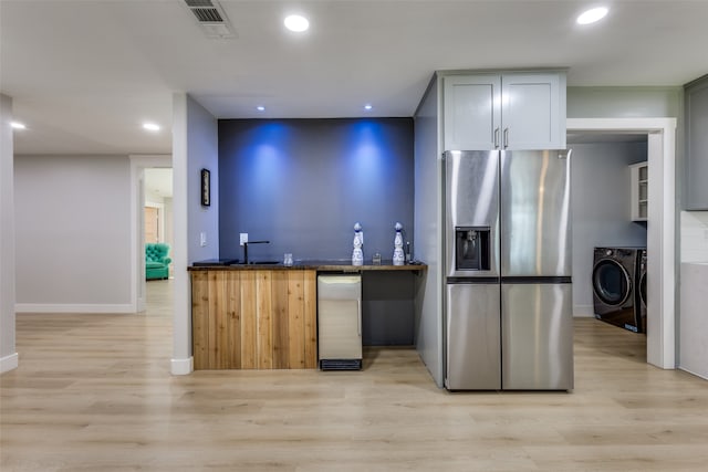 kitchen featuring light wood-type flooring, washing machine and clothes dryer, and stainless steel fridge