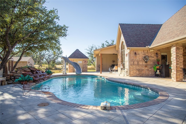 view of swimming pool featuring a water slide and a patio area