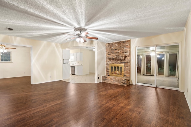 unfurnished living room with a fireplace, wood-type flooring, ceiling fan, and a textured ceiling