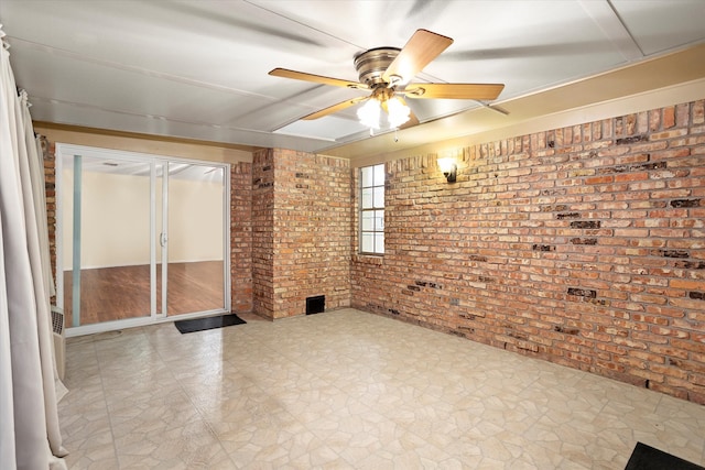 empty room featuring light hardwood / wood-style flooring, brick wall, and ceiling fan