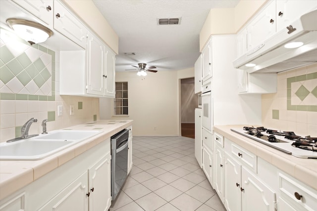 kitchen featuring tile countertops, white appliances, and white cabinets