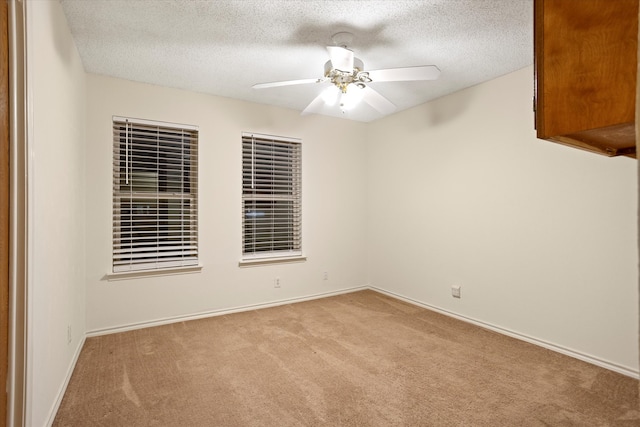 carpeted spare room with a textured ceiling and ceiling fan