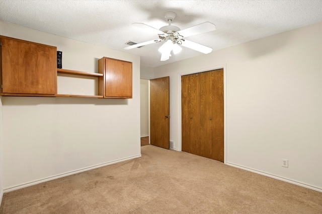 empty room featuring ceiling fan, light colored carpet, and a textured ceiling