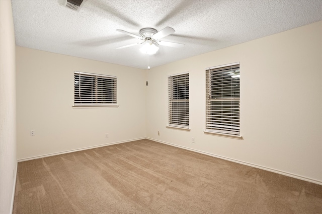 empty room with a textured ceiling, light colored carpet, and ceiling fan