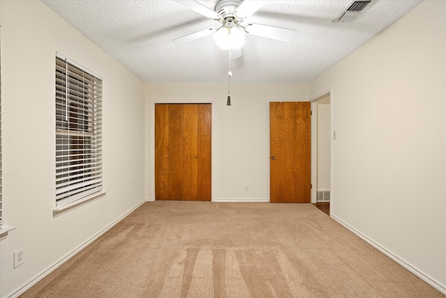 interior space with a closet, a textured ceiling, light carpet, and ceiling fan