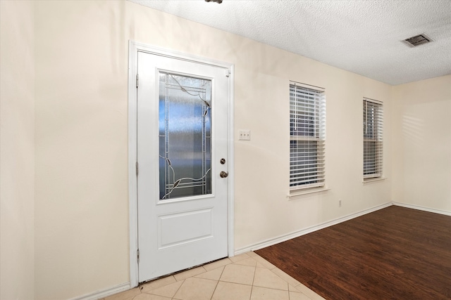 entrance foyer with a textured ceiling and light hardwood / wood-style floors