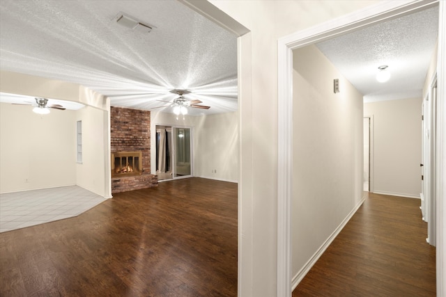 unfurnished living room with a fireplace, dark wood-type flooring, and a textured ceiling