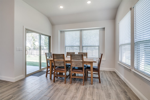 dining area featuring a healthy amount of sunlight, light wood-type flooring, and vaulted ceiling