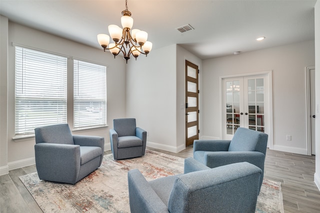 living room with an inviting chandelier, a wealth of natural light, french doors, and hardwood / wood-style flooring